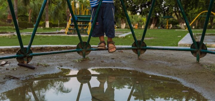 Young boy standing near a jungle gym with reflection