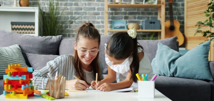 Woman and child drawing together on a couch.